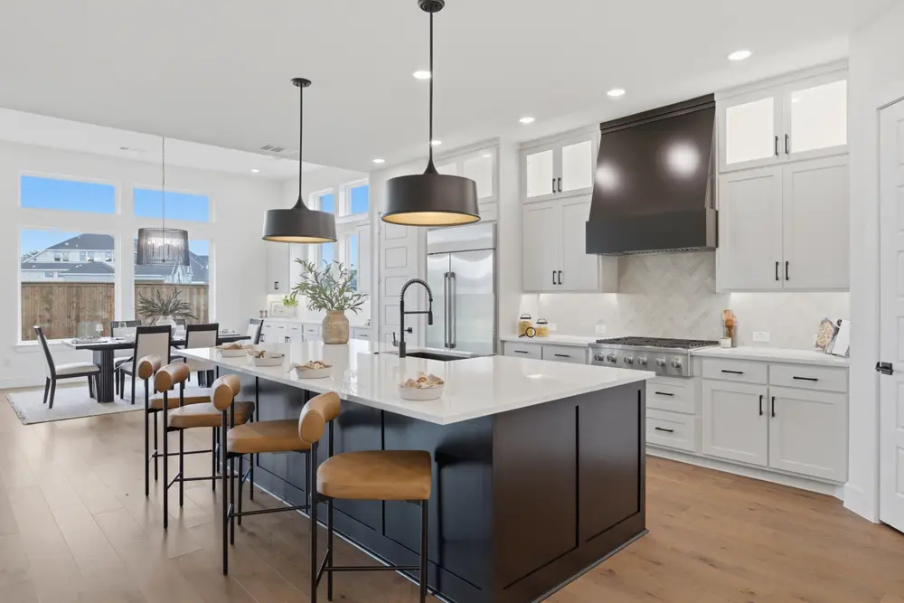 Kitchen with navy island, wood range hood and dining nook