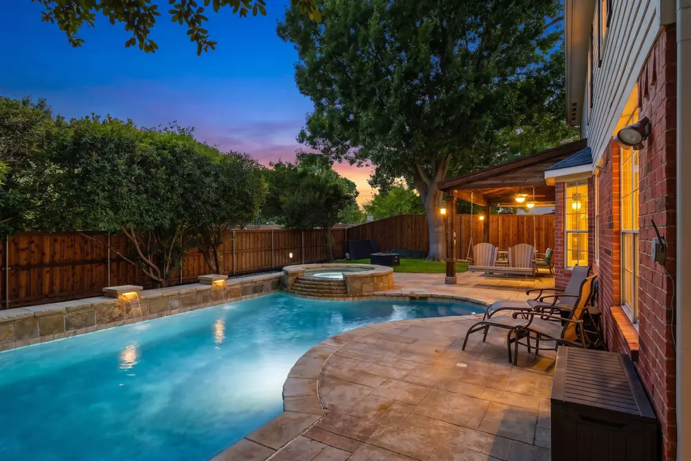 Twilight pool and spa with stone waterfalls and a covered patio